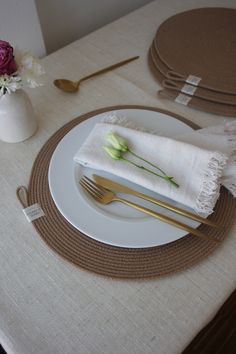 a white plate topped with a fork and knife next to a vase filled with flowers