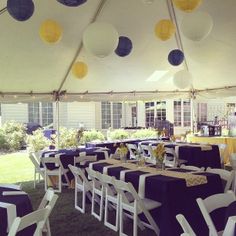 tables and chairs are set up under a tent with paper lanterns hanging from the ceiling