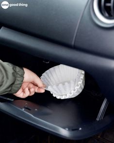 a person holding a paper cup in their hand near the inside of a car door