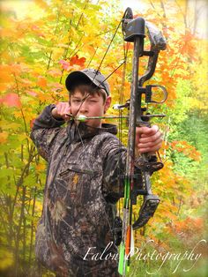 a young boy is holding his bow and aiming it at the camera with an arrow