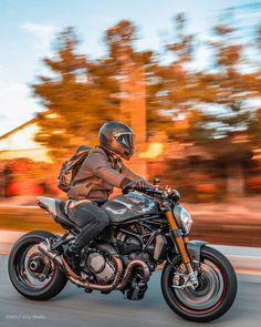 a man riding on the back of a motorcycle down a street