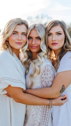 three beautiful women hugging each other in front of the camera with their arms around one another