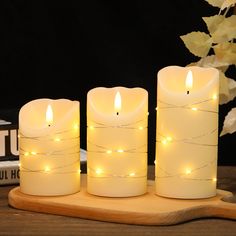 three lit candles sitting on top of a wooden board