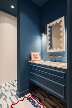 a bathroom with blue walls and an art work on the wall above the vanity area