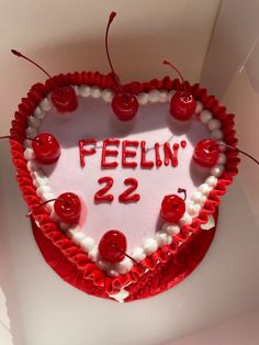 a heart shaped cake with the words feelin'22 on it and cherries