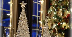 a crystal christmas tree sitting on top of a table next to a wine glass holder