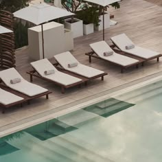 four lounge chairs sitting next to a swimming pool