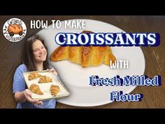 a woman holding a tray with croissants on it