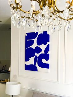 a chandelier hanging from the ceiling in a living room with blue and white artwork