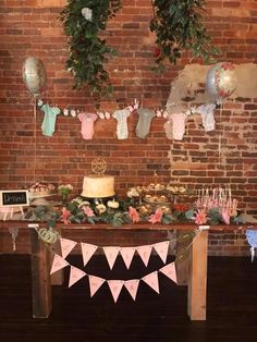 a table with cake and cupcakes on it in front of a brick wall