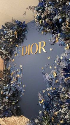 the dior logo is surrounded by blue and gold flowers on display in front of a wall