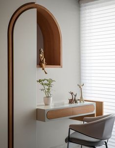 an arch in the corner of a room next to a desk with a chair and potted plant