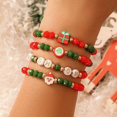 a close up of a person's arm wearing bracelets with christmas decorations on them