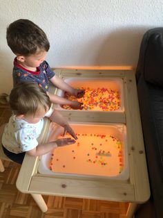 two toddlers are playing with their play trays