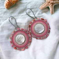 pink and white beaded earrings sitting on top of a bed next to starfish