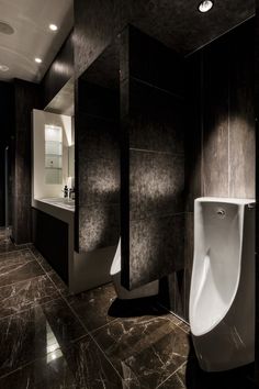 a urinal and sink in a bathroom with black marble flooring on the walls