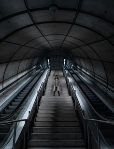 a woman is standing on an escalator in a tunnel