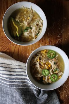 two bowls filled with soup sitting on top of a wooden table next to a towel