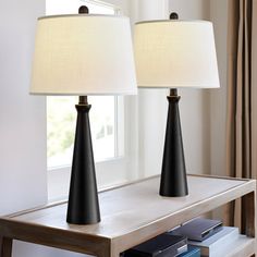 two black lamps sitting on top of a wooden table