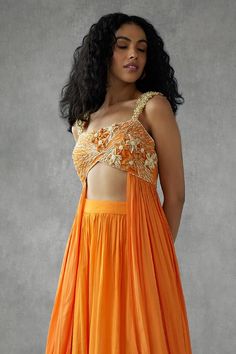 Saffron orange sleeveless sweetheart neck padded blouse with all over lily floral applique, beads embellishments and side panel detail. Paired with matching flared sharara.
Components: 2
Pattern: Embroidery
Type Of Work: Beads, Floral Applique
Neckline: Sweetheart Neck
Sleeve Type: Sleeveless
Fabric: Georgette Crepe
Color: Orange
Other Details: 
Attached inner lining
Padded blouse
Approx. weight: 1kgs
Length:
Sharara: 44inches
Blouse : 13inches
Occasion: Sangeet, Mehendi and Haldi - Aza Fashions Bollywood Style Hand Embellished Festive Tops, Festive Bollywood Hand Embellished Tops, Hand Embellished Tops For Wedding, Embellished Sleeveless Choli For Reception, Festive Hand Embellished Tops For Reception, Elegant Hand Embellished Georgette Top, Sleeveless Choli With Pearl Embroidery For Festive Occasion, Bollywood Style Embellished Top For Reception, Festive Embellished Tops For Wedding