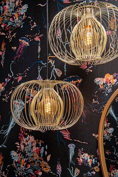 three light fixtures hanging from the ceiling in a room with floral wallpaper and black walls