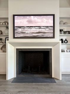 a painting hanging on the wall above a fire place in a room with white walls