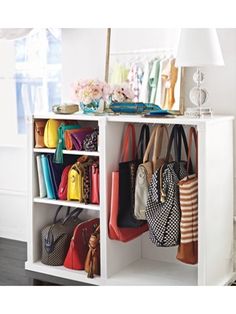 several purses and handbags are hanging on a shelf in a room with white walls