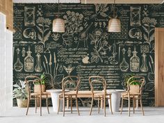 a dining room with green wallpaper and wooden chairs in front of a table surrounded by potted plants