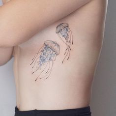 a woman's stomach with two jellyfish tattoos on it