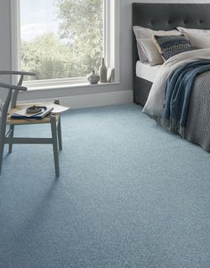 a bedroom scene with focus on the bed and blue carpeted flooring that looks like it has been cleaned