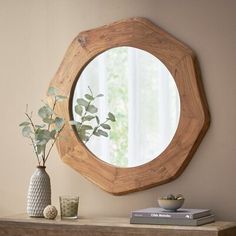 a mirror on the wall above a table with a vase and plant in front of it