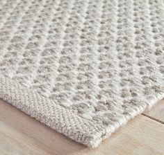 a close up view of a rug on a wooden floor with white and gray colors