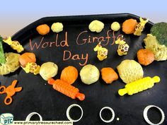 a black tray topped with lots of different types of vegetables and words that say world giraffe day