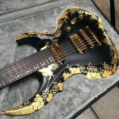 a black and gold guitar laying on top of a carpet