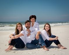 three people sitting on the beach with their arms around each other and smiling at the camera