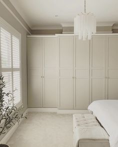 a bedroom with white walls and carpeted flooring next to a plant in the corner