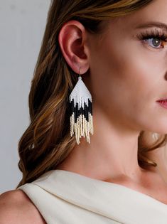 These stunning earrings in matte white, black, and cream are perfect for fall. All of our seed bead earrings are hand sewn one bead at a time by women working to rise out of poverty. Materials - glass beads, 14k gold plated hook Measurements - 3 1/2’ L x 1 1/4’ W including hook White Beaded Earrings With Black Beads, Elegant White Handwoven Earrings, White Handwoven Beaded Drop Earrings, White Drop Earrings With Black Beads, Black And Gold Beaded Earrings, Black And White Fringe Earrings, Black Handwoven Beaded Earrings, Elegant Handwoven Black Beaded Earrings, Elegant Black Handwoven Beaded Earrings