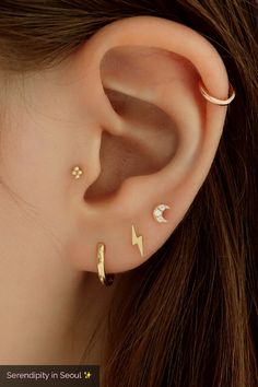 an ear with three different piercings on the top and one has a lightning bolt