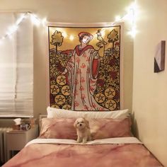 a white dog sitting on top of a bed next to a wall hanging above it