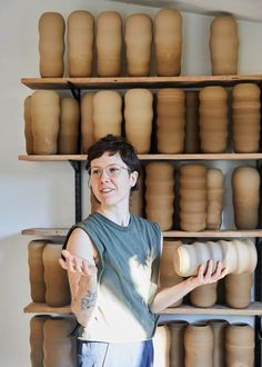 a man standing in front of stacks of clay pots