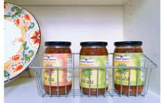 three jars of jam sitting on top of a metal rack next to a white plate