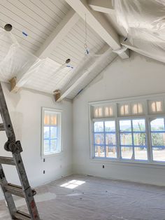 an empty room with two windows and a ladder