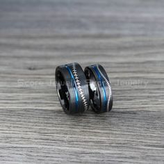 two black and blue wedding bands with the word love written on them, sitting on a wooden surface