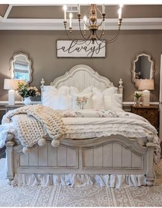 a white bed sitting under a chandelier in a bedroom