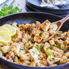 a skillet filled with chicken and lemons on top of a wooden cutting board