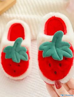 someone is holding up a pair of red and white slippers with green leaves on them