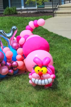 an inflatable cat is sitting on the grass next to some balls and balloons