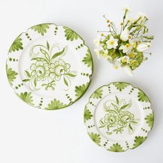 two green and white plates sitting next to each other with flowers in the middle on them