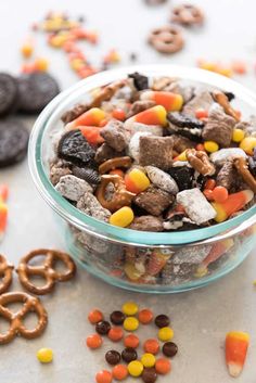 a glass bowl filled with cereal and pretzels on top of a white table