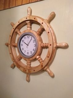 a clock mounted to the side of a ship's steering wheel on a wall